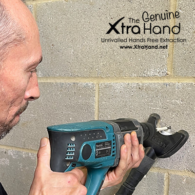 Tradesperson drilling into a concrete block wall with the Genuine XtraHand® hands-free dust extraction tool capturing dust at the source.